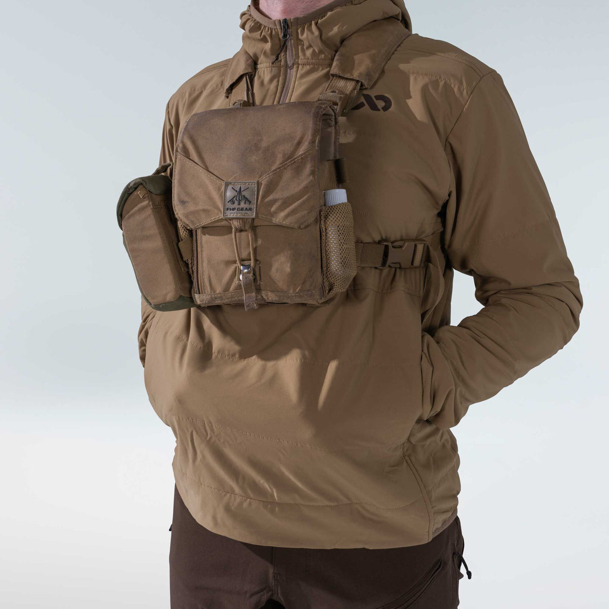 Coyote brown FHF GEAR chest pack with a flap pocket, side utility pouch, and mesh bottle holder, worn over a brown jacket.