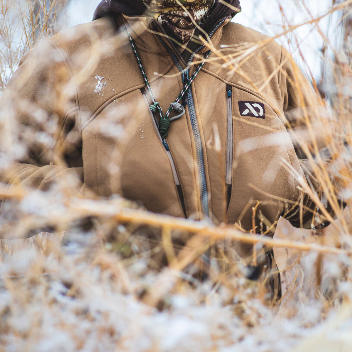 Tan fleece jacket with a full zipper, zippered chest pocket, logo, and an outdoor lanyard.