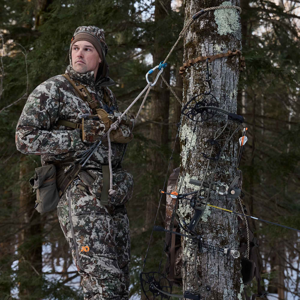 Man up on a tree wearing camo jacket and pants.