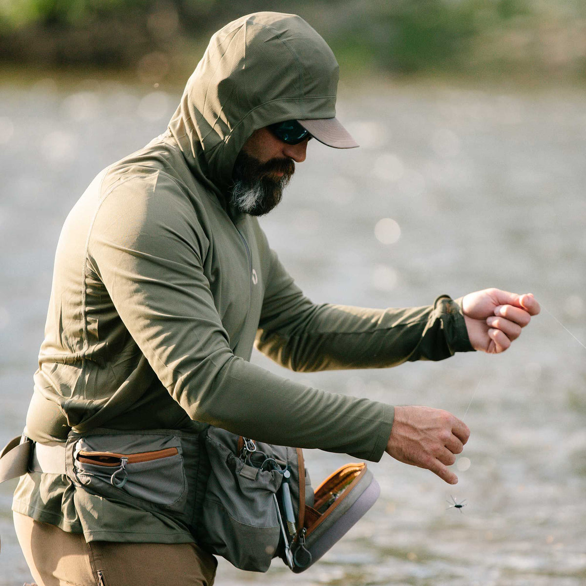 Olive green hooded long-sleeve sun shirt worn by a man fly fishing.