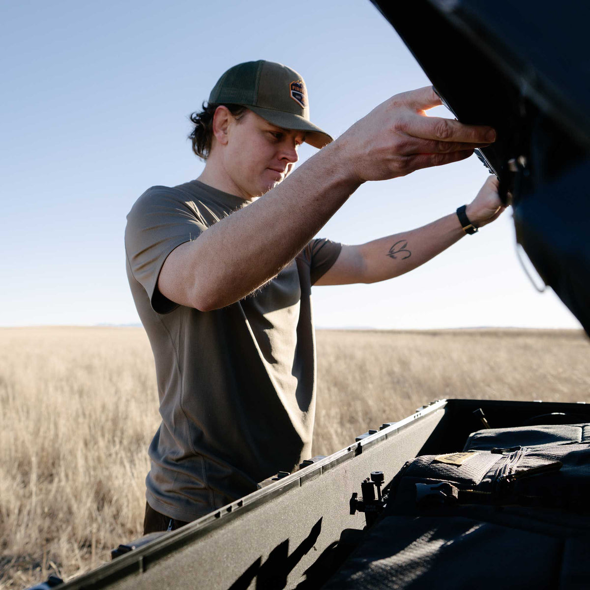 A dark rugged hard case is open, revealing a padded interior with modular organizers and securing straps.
