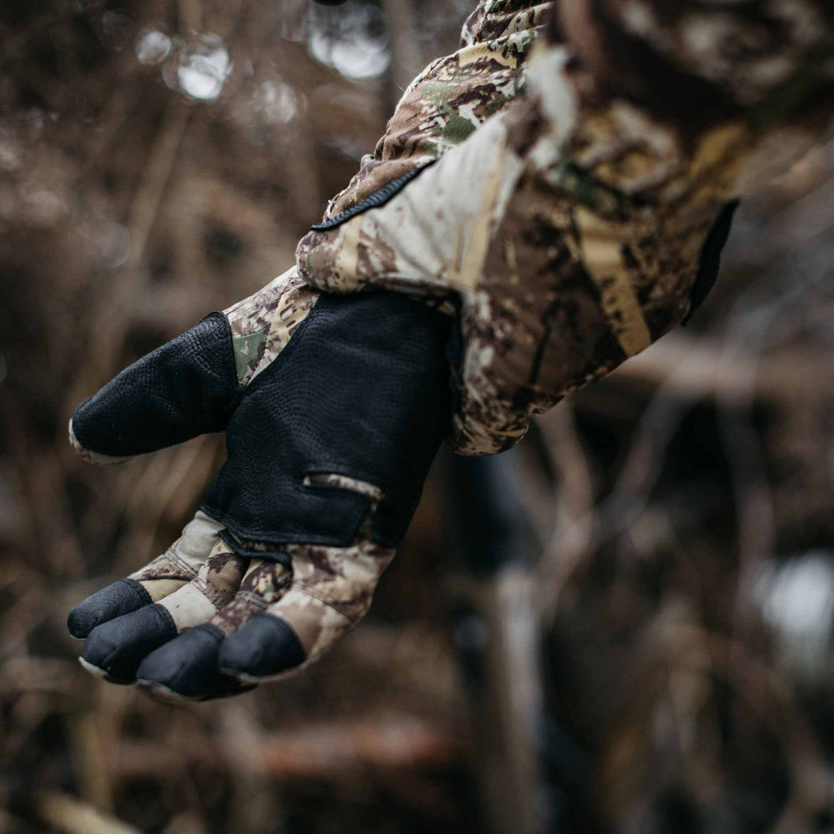 Camouflage glove with black reinforced palm and fingertips, featuring slits on the index and middle fingers.