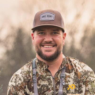 Brown ONX HUNT logo trucker cap worn by a man.