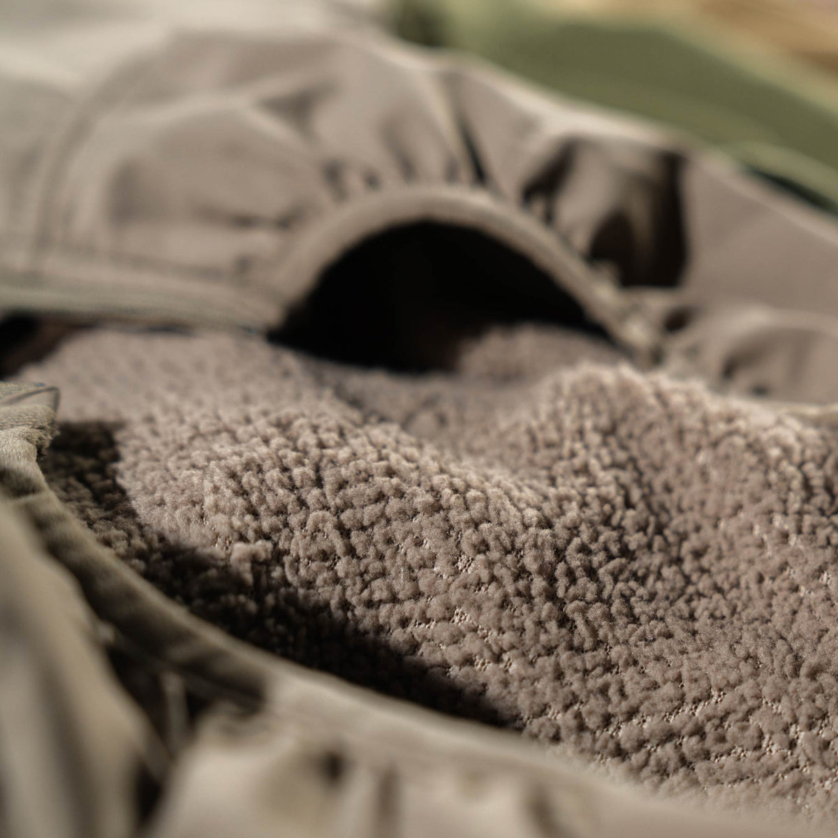 Close-up of a muted olive jacket revealing its fuzzy Walnut sherpa lining.
