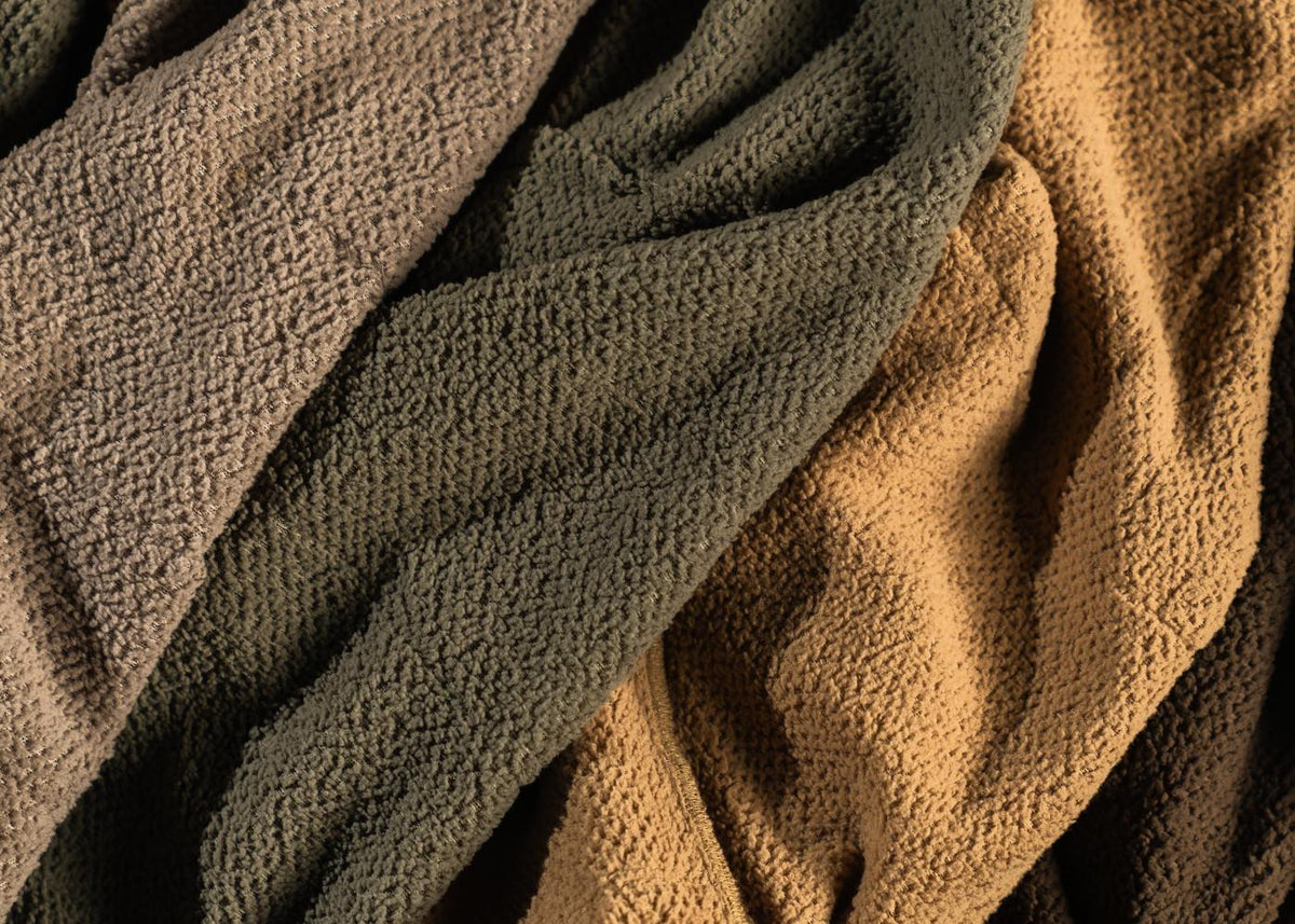 Draped taupe, olive, and tan textured fabrics showing a bubbly surface.