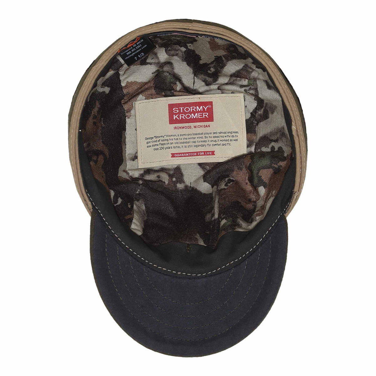 An olive green Stormy Kromer cap, viewed from above, has a dark blue brim, tan inner band, and a camouflage lining with prominent brand and size labels inside.