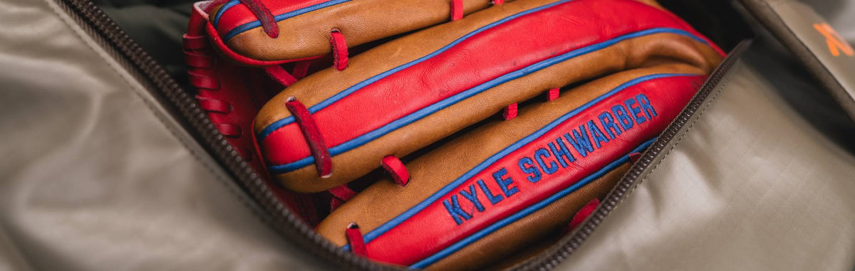 Tan catcher's mitt with red lacing, blue stripes, and KYLE SCHWARBER embroidered.