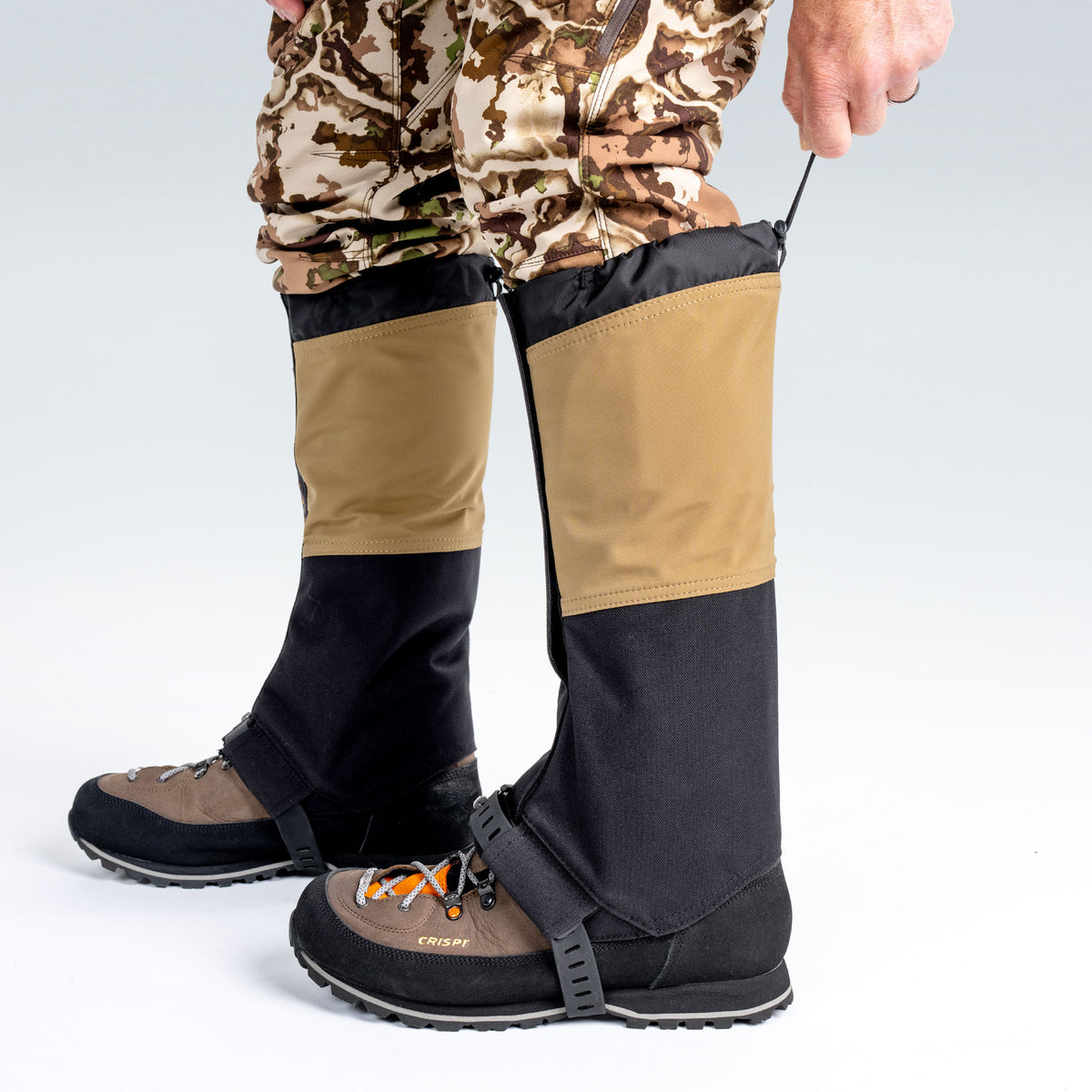 Side view of model wearing boot gaiters, adjusting top cuff