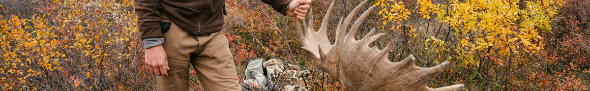 Person holding large, light brown moose antler with many tines.