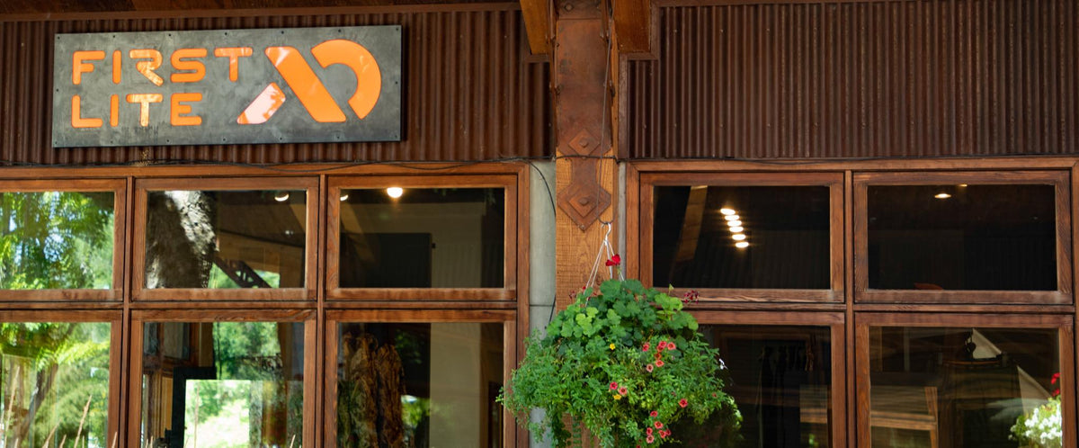 First Lite storefront with grey & orange sign, brown corrugated metal, wooden windows.