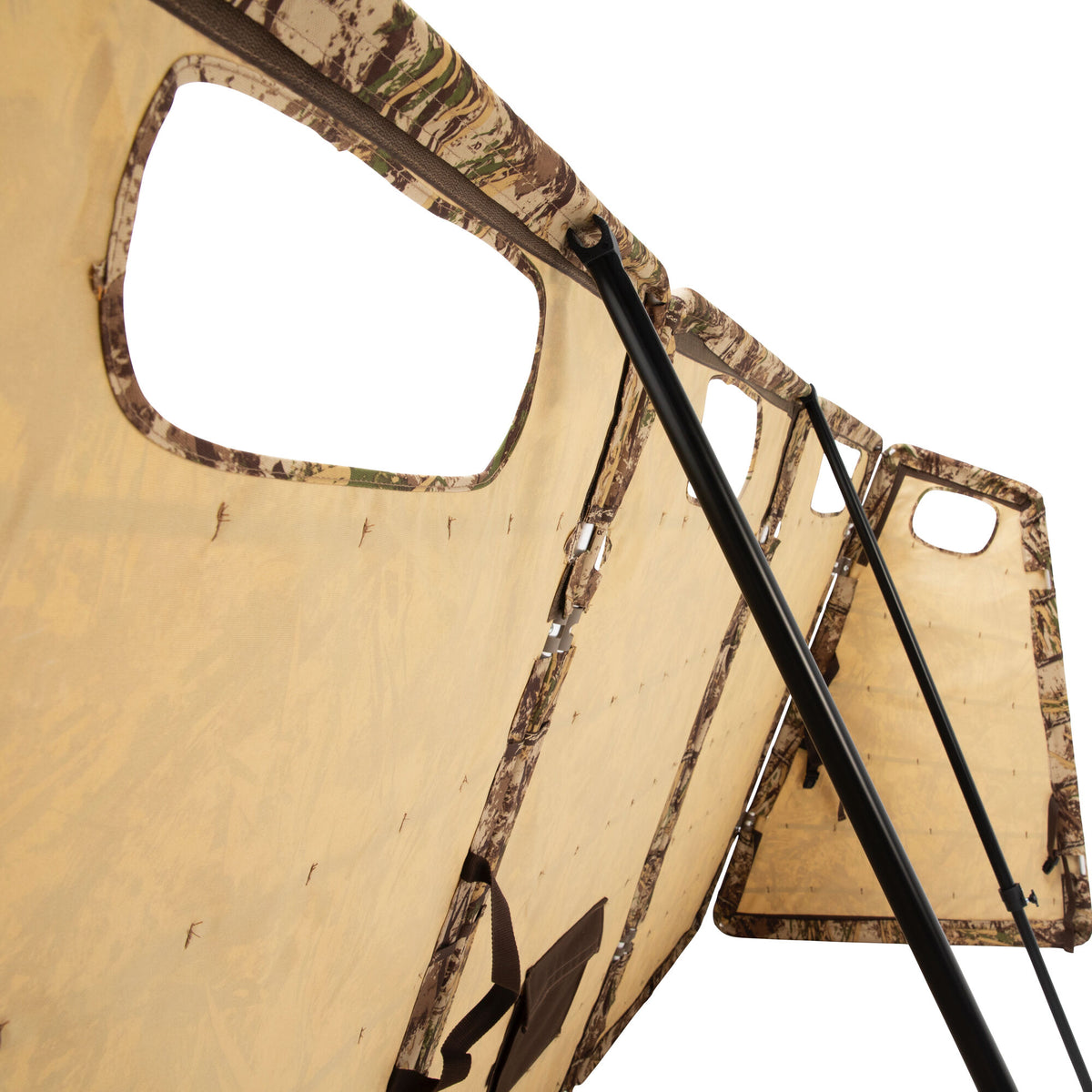 Tan and camouflage multi-panel hunting ground blind with black support poles and viewing windows.