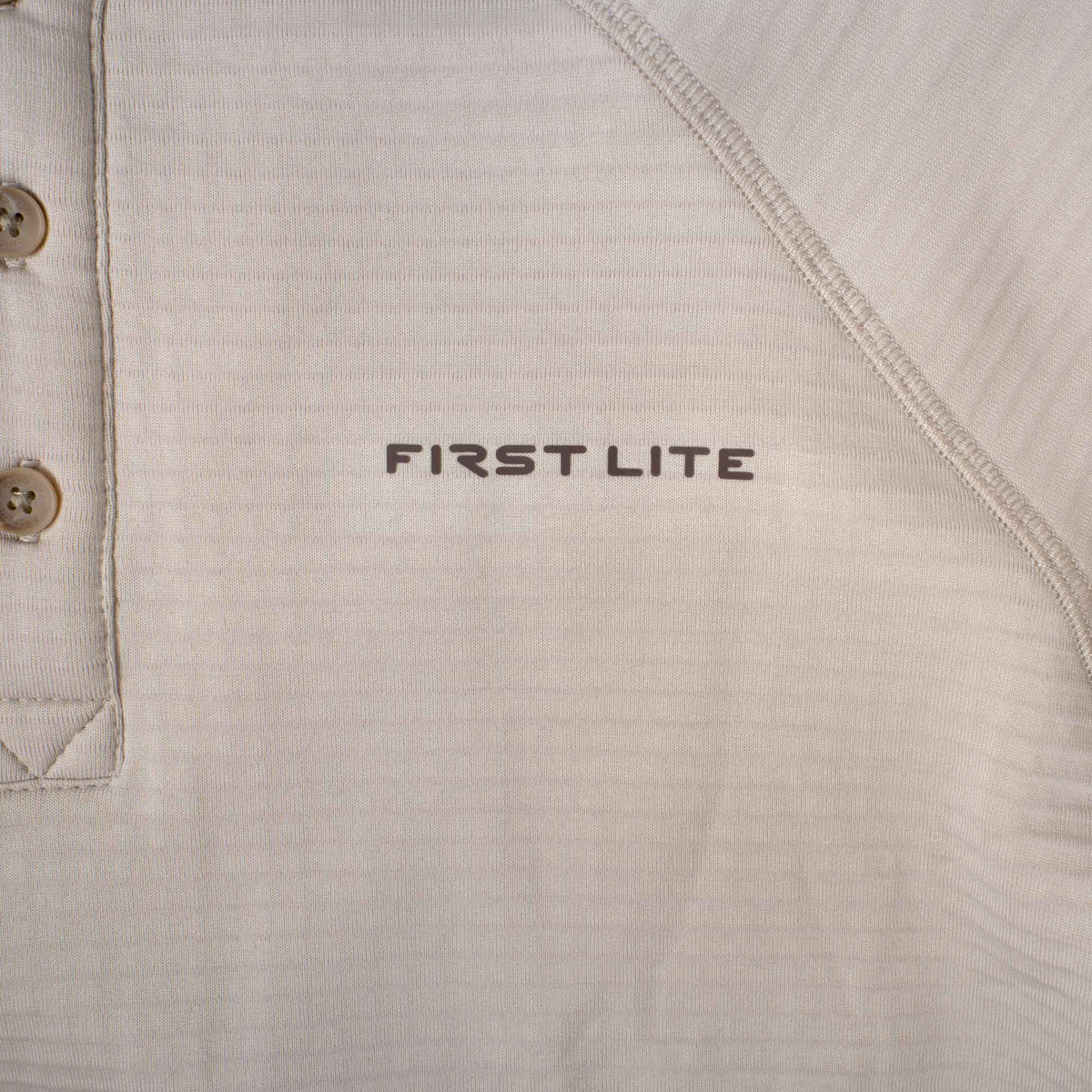 Light brown long-sleeve shirt with a 3-button placket, visible flatlock seams, and "FIRST LITE" logo.