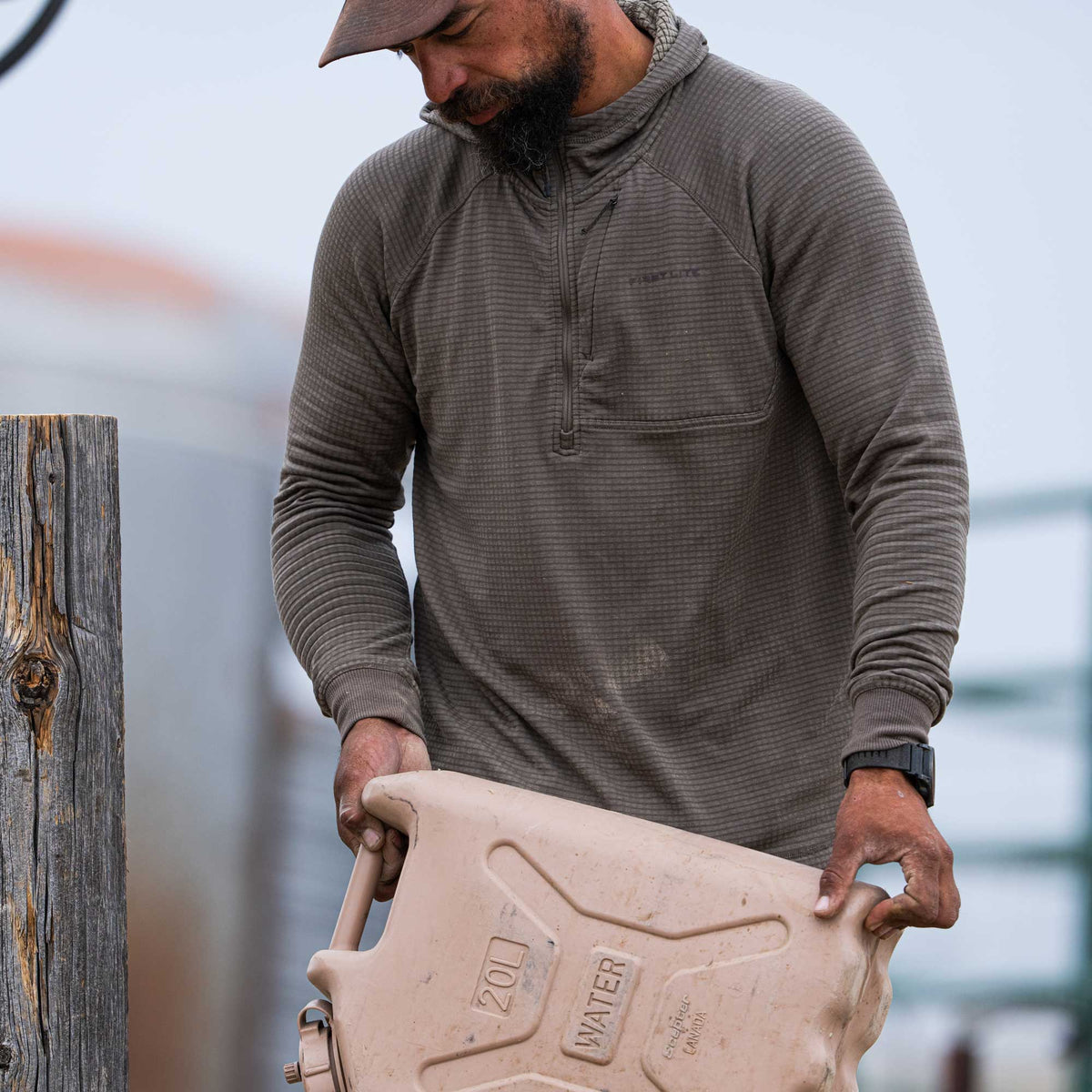 A man wears an olive brown textured hooded quarter-zip pullover with a chest pocket and a visible FIREFLYTE logo.