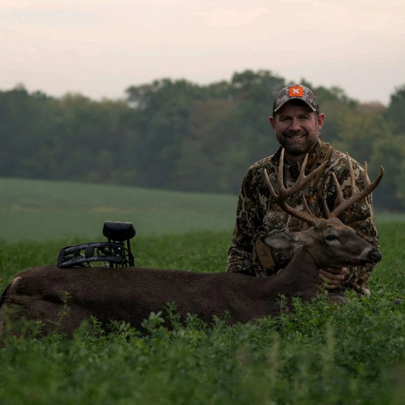 Smiling hunter with trophy buck and black INLINE hunting bow on its back.
