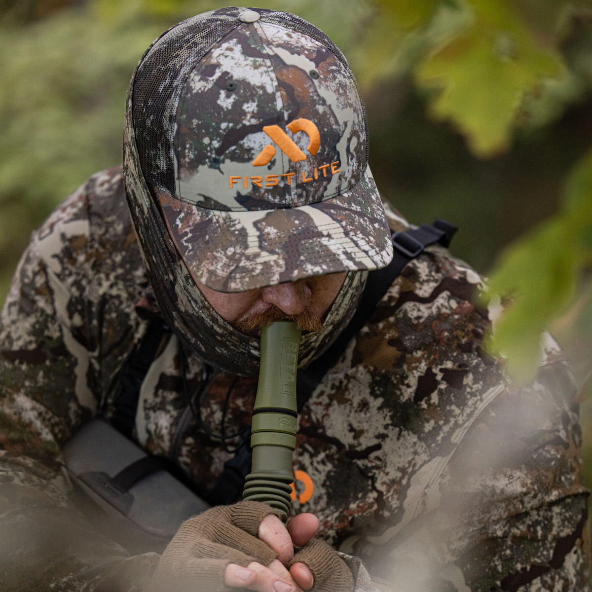 Olive green BETA PRO hunting game call with a ribbed base, being used by a hunter in camouflage.