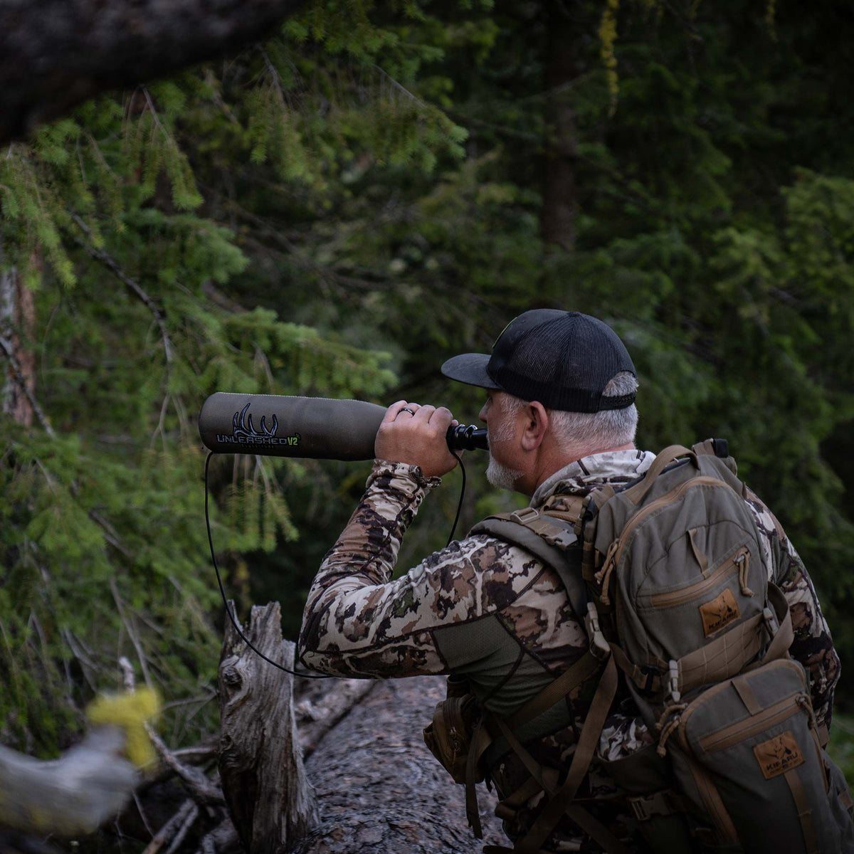 Olive green Unleashed V2 game call with an antler logo being used in a forest.