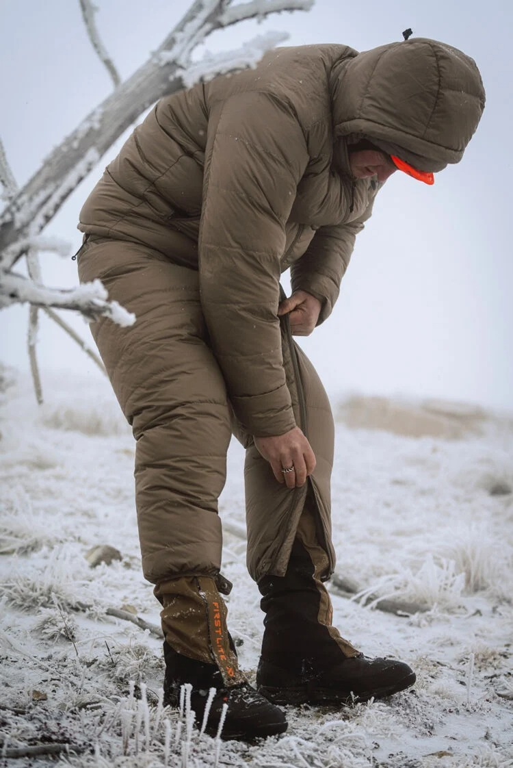 Brown hooded puffy suit with leg zippers, worn in snow.