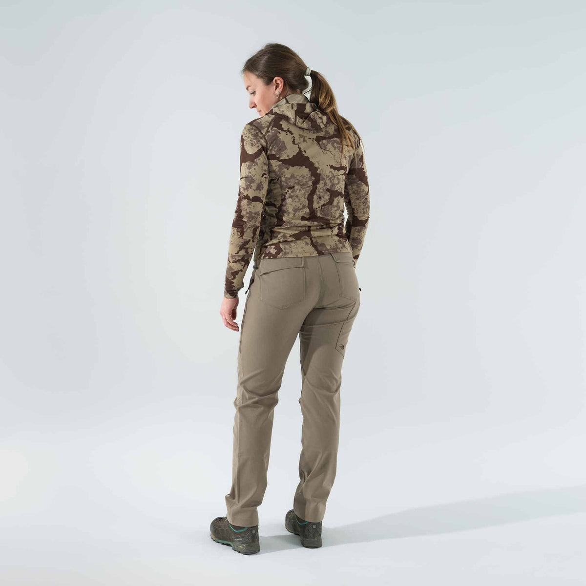 Woman from behind wearing a brown camouflage long-sleeve hooded top and khaki utility pants.