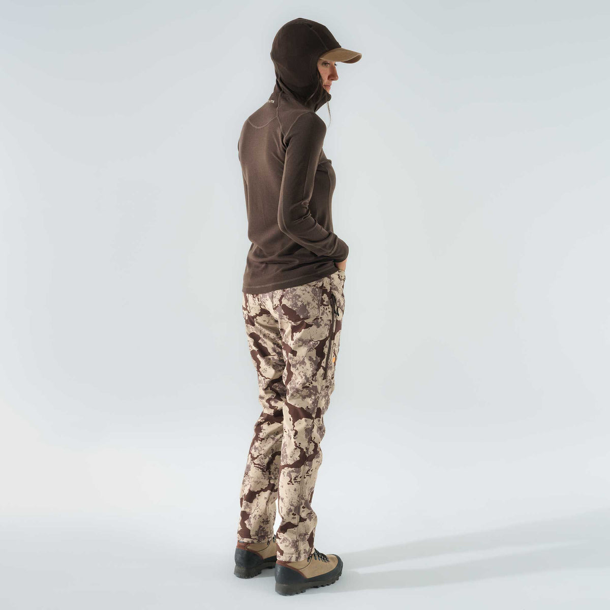 Woman wearing a dark brown hooded long-sleeve shirt and brown and tan camouflage pants.