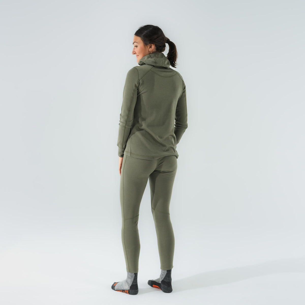 A model wears a fitted olive green base layer set with a high neck and visible flatlock seams.