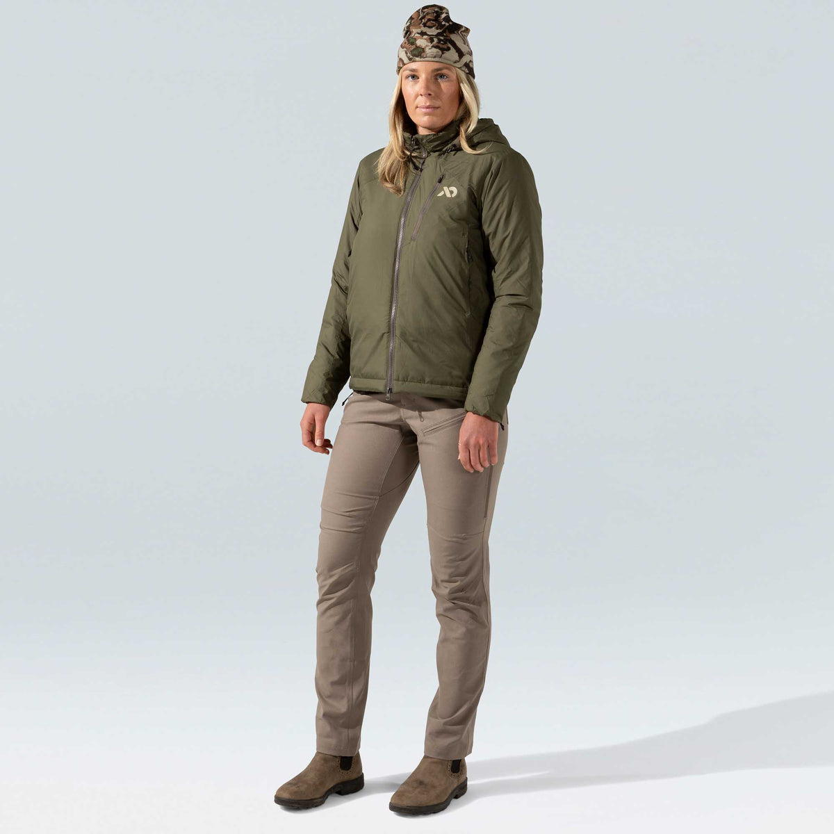 A woman wears an olive green hooded jacket with a full front zipper and a light beige logo on the left chest.