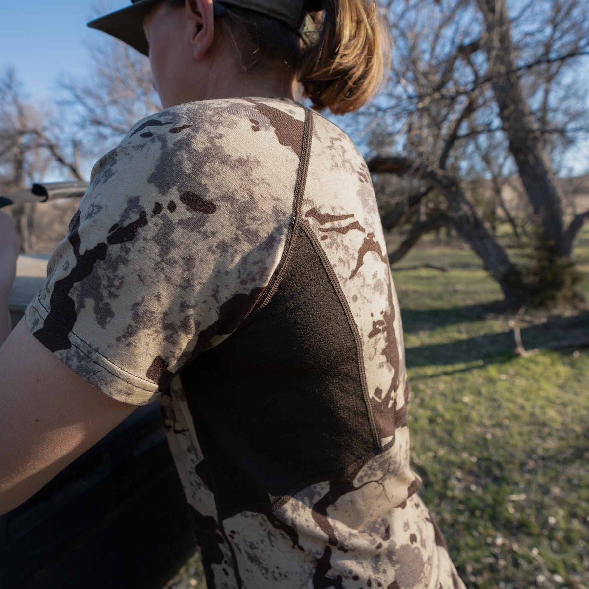 Short-sleeve camouflage shirt with a light tan, dark brown, and grey pattern, featuring prominent dark brown textured side panels.