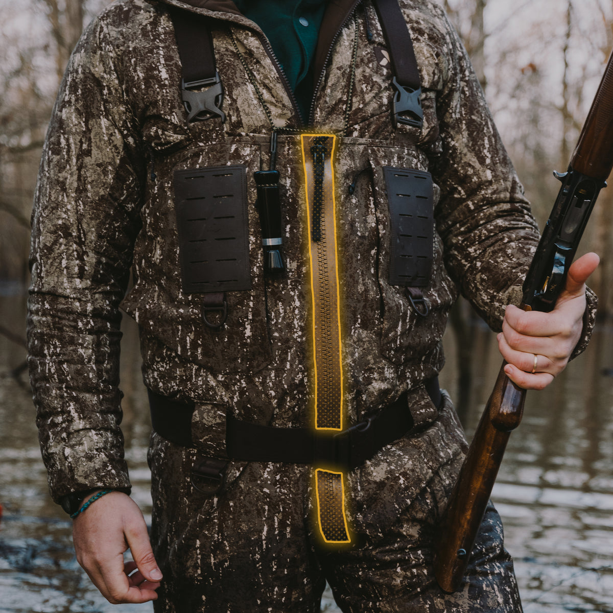 Dark camo hunting waders with front zipper, chest panels, and suspenders.